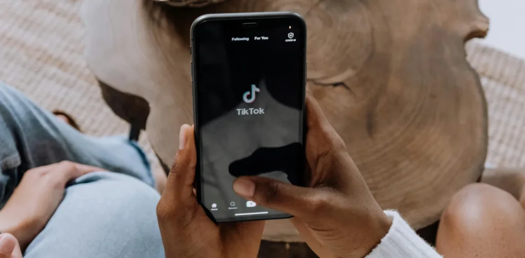 someone holding a phone showing a tiktok homepage