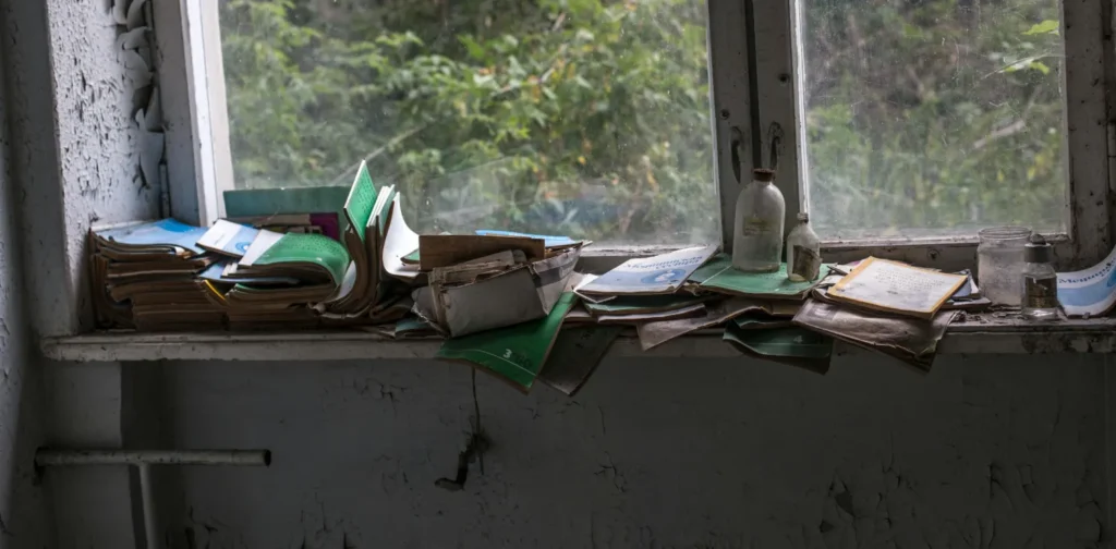 a stack of abandoned books at a windowsill