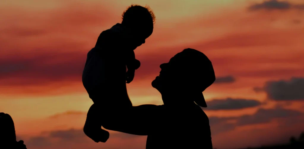A silhouette of a father carrying his child