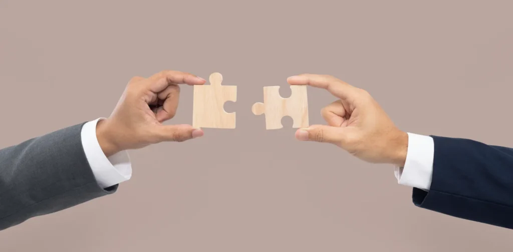 two hands joining puzzle pieces