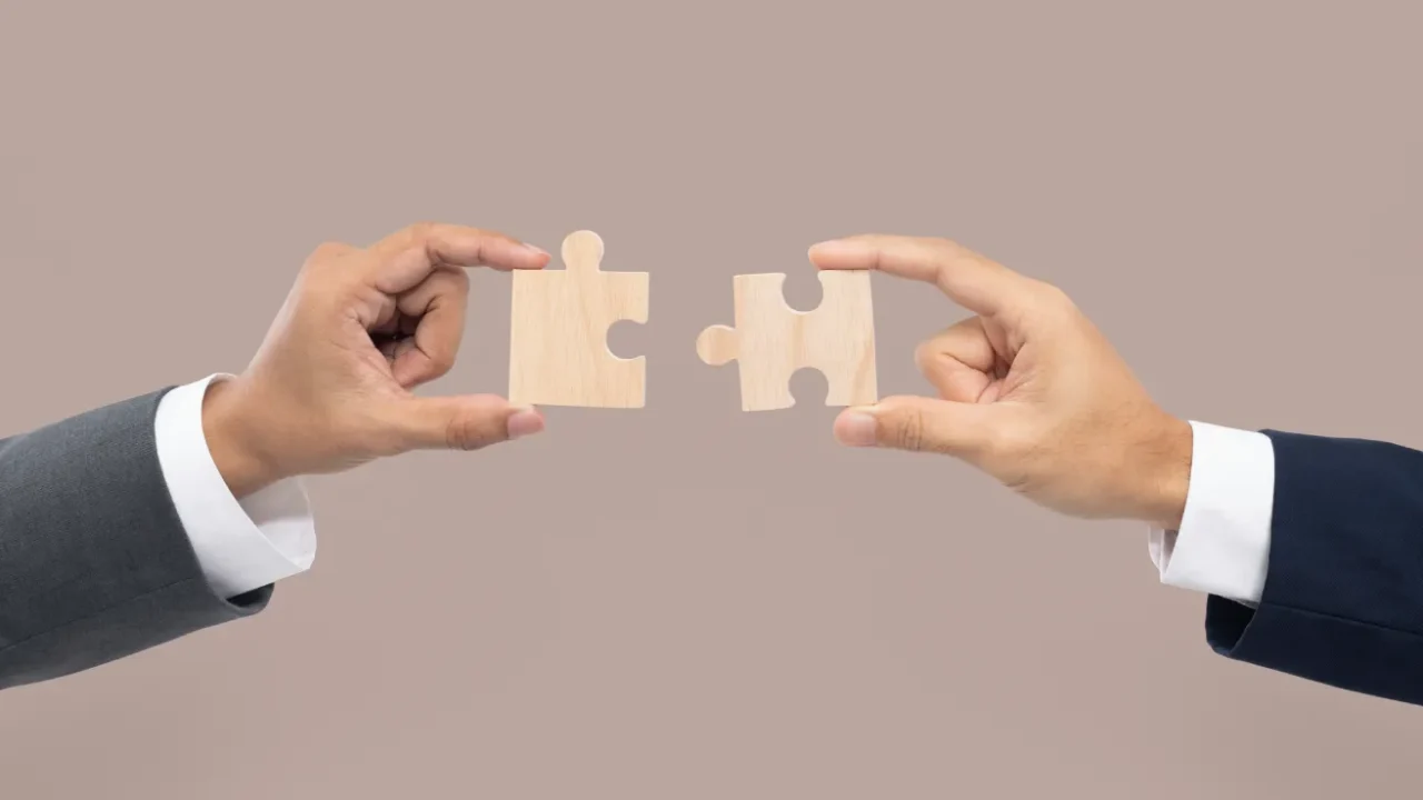 two hands joining puzzle pieces