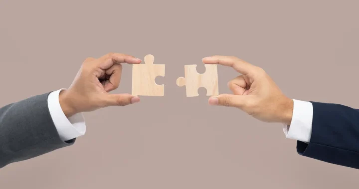 two hands joining puzzle pieces