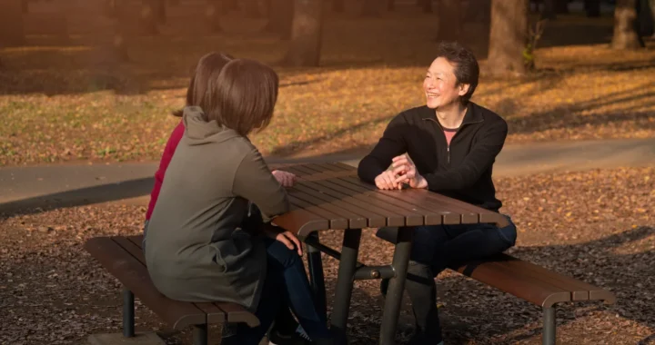 people sitting and talking on a wooden bench
