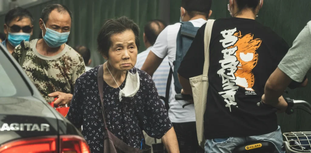 An elderly walk in the crowd.