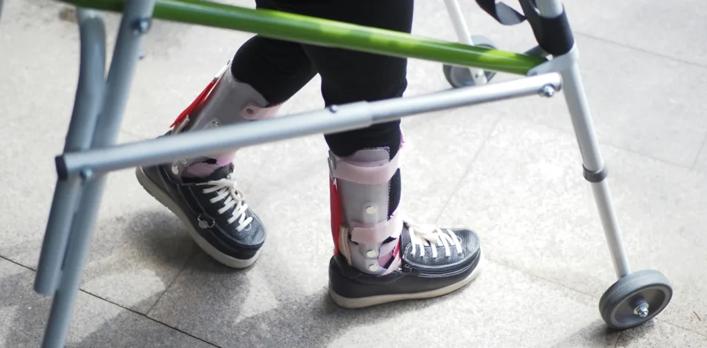 a pair of legs wearing assistive shoes and a crutch
