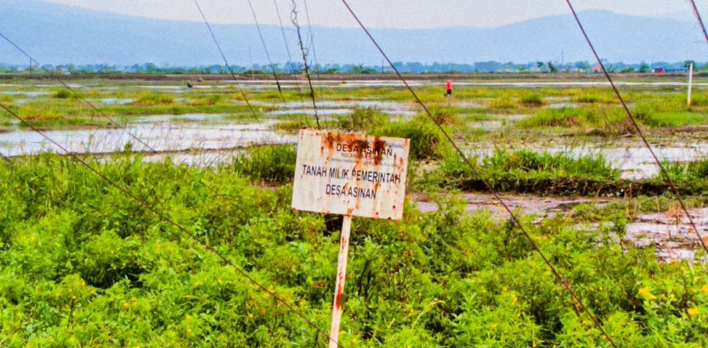 a wooden board saying the land belongs to the asinan village government planted near the border of a lake called rawa pening