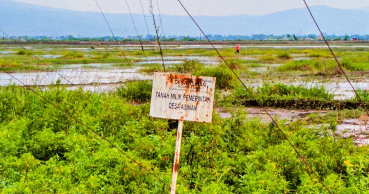 a wooden board saying the land belongs to the asinan village government planted near the border of a lake called rawa pening
