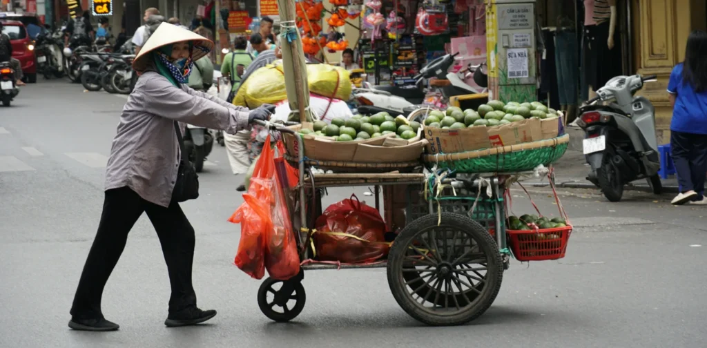 a street vendor pushing her cart across the street