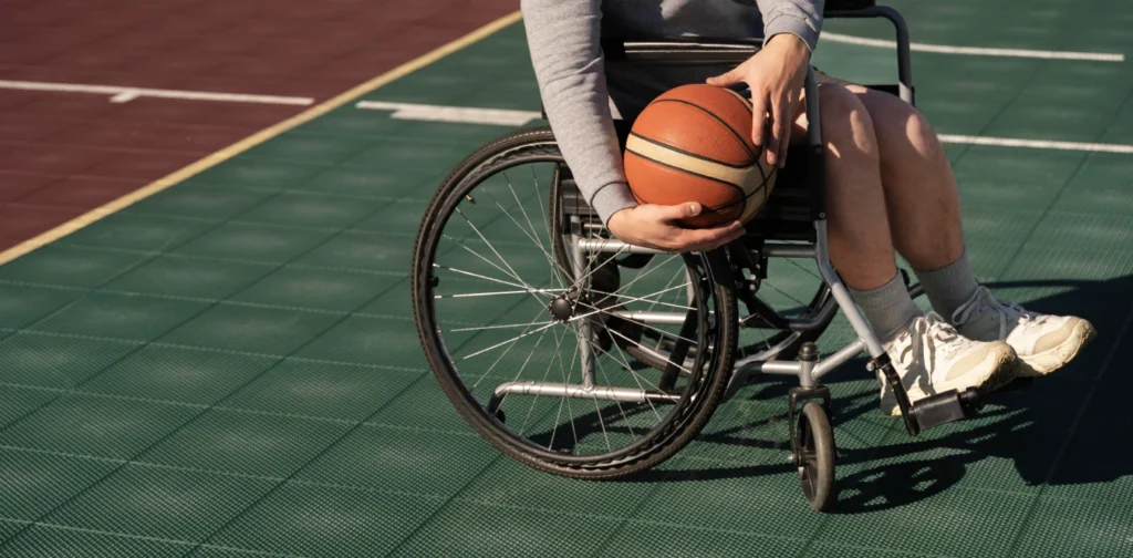 A disabled person in a wheelchair holding a basketball on the court.