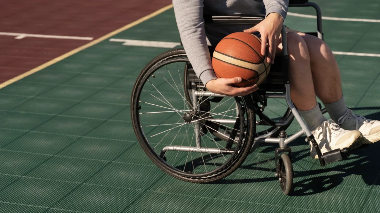 A disabled person in a wheelchair holding a basketball on the court.