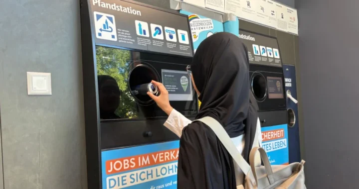a woman in hijab putting an empty can into a recycling machine