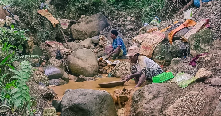 two women separating gold from sand using a pan