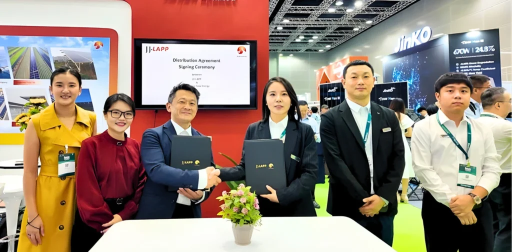 six people standing side by side, with two shaking hands in the middle