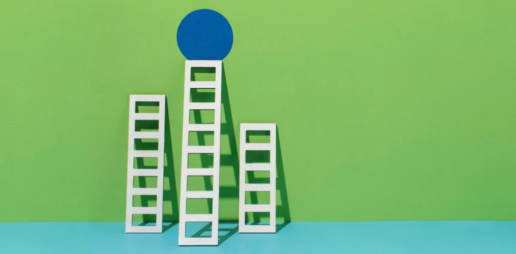 three ladders with different height propped against a wall