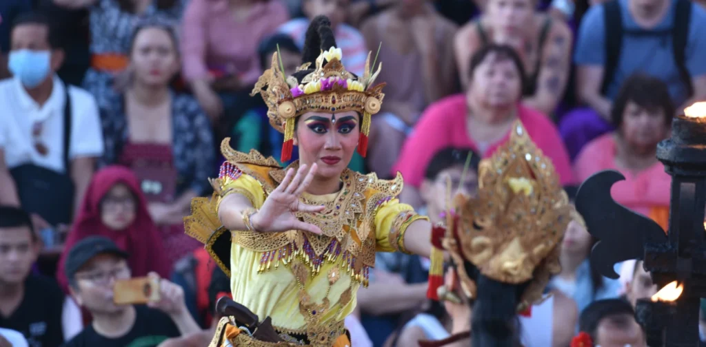 Two women perform a Balinese dance in front of the audience.