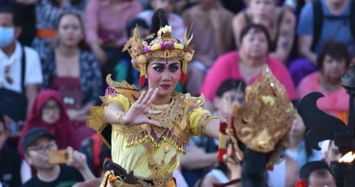 Two women perform a Balinese dance in front of the audience.