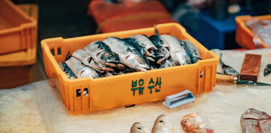 a tray of fish with other seafood and knives surrounding it on a board