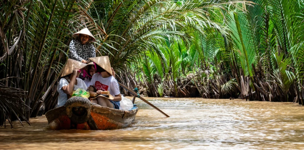 A group of people riding a boat on the mekong river surrounded by trees