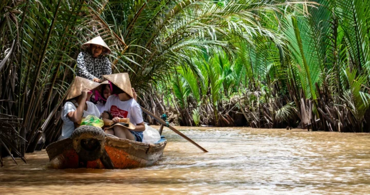 A group of people riding a boat on the mekong river surrounded by trees