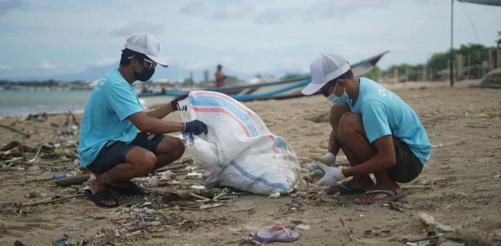 two men collecting waste on a beach