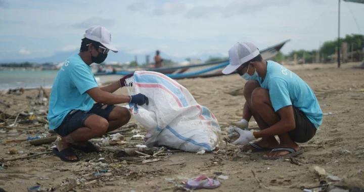 two men collecting waste on a beach
