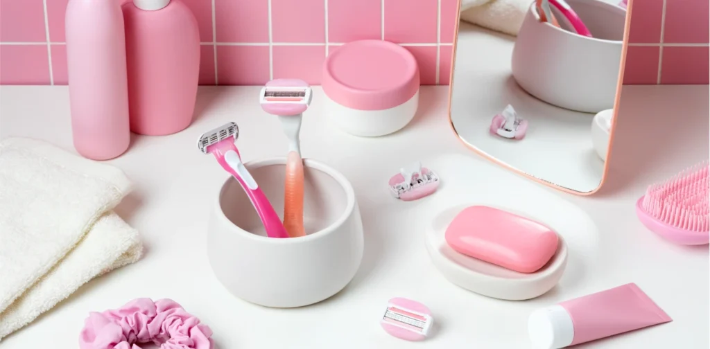 Pink-themed personal care products, including razors, lotion, and soap, arranged neatly on a bathroom counter.