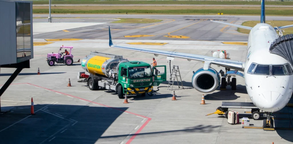 a green and yellow truck to refuel an airplane at the airport during daytime