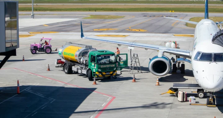 a green and yellow truck to refuel an airplane at the airport during daytime