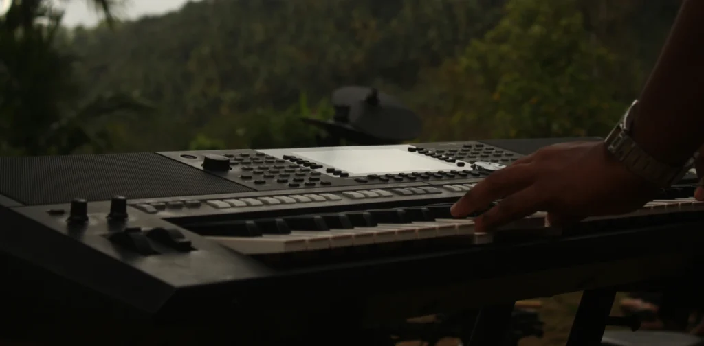 hands playing keyboard in front of a forest