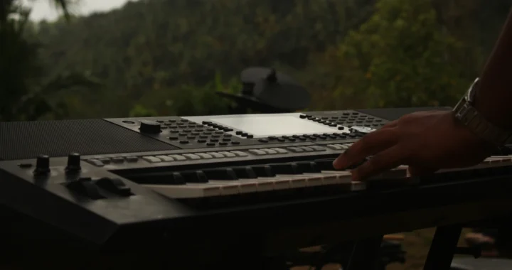 hands playing keyboard in front of a forest