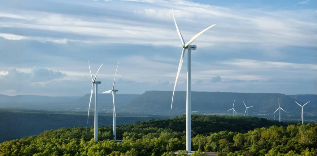 a group of wind turbines on top of a green hillside with a clear sky