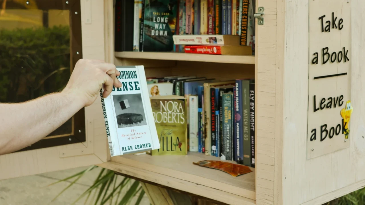 Someone is reaching for a book from a little free library stand