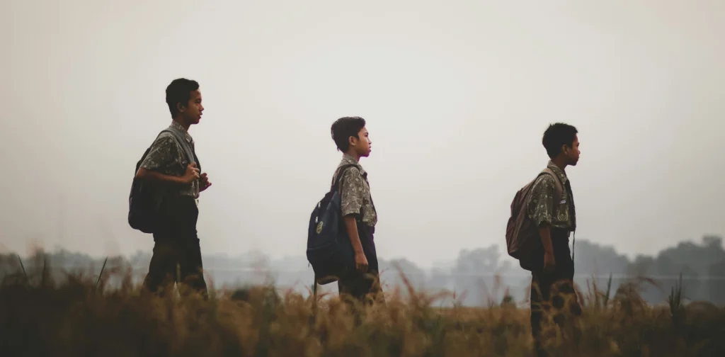 three students walking in a field