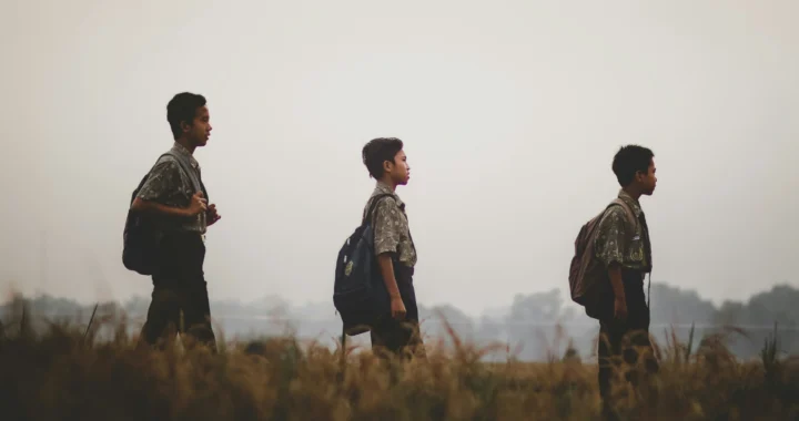 three students walking in a field