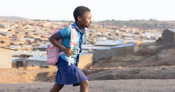 a child in uniform with a backpack walking uphill