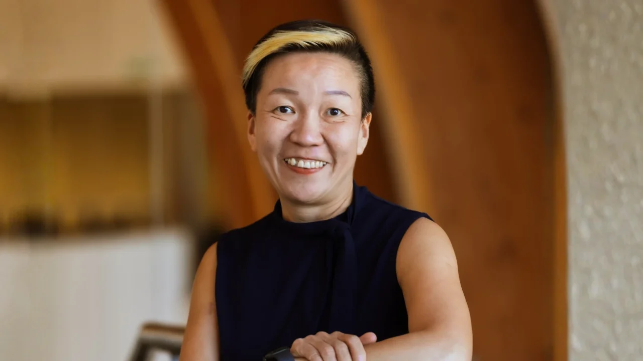 May Tan-Mullis, a woman with short hair wearing a black blouse smiling at the camera