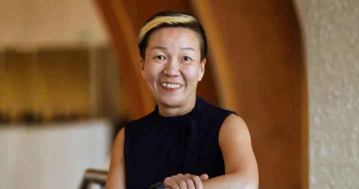 May Tan-Mullis, a woman with short hair wearing a black blouse smiling at the camera