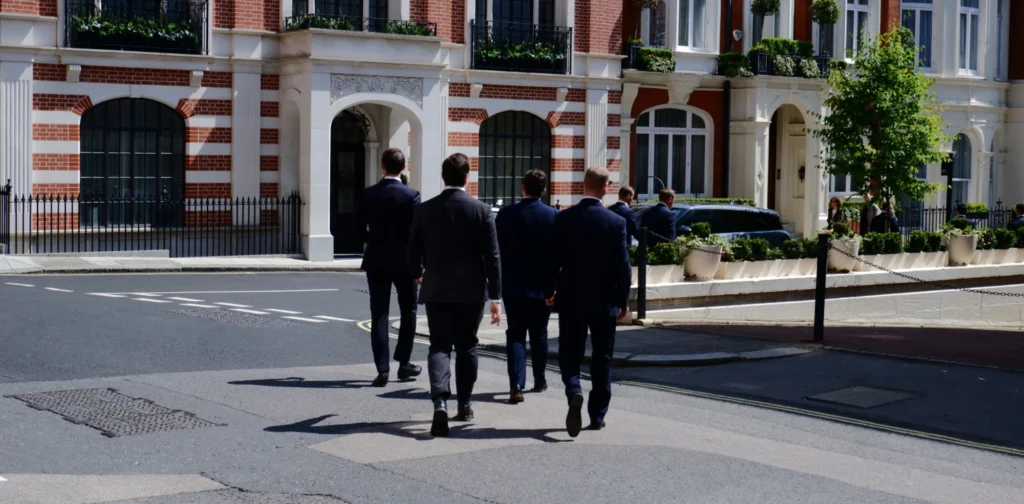 a bunch of men in suits crossing the street
