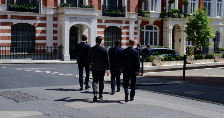 a bunch of men in suits crossing the street