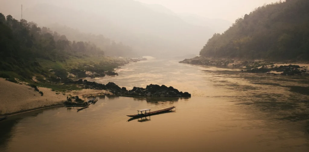 aerial view of river with a boat and hills on the side