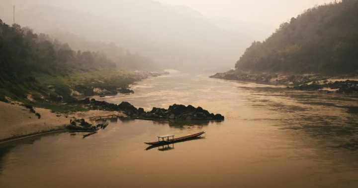aerial view of river with a boat and hills on the side