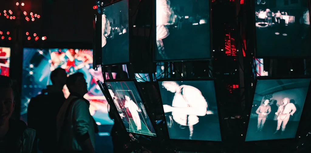 a group of people standing around a display of video screens