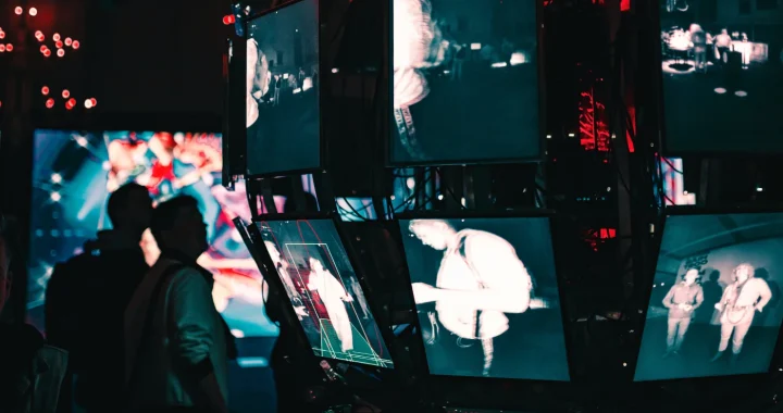 a group of people standing around a display of video screens