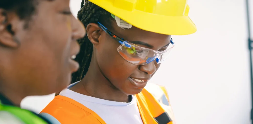 two women in protective gear examining an electricity circuit