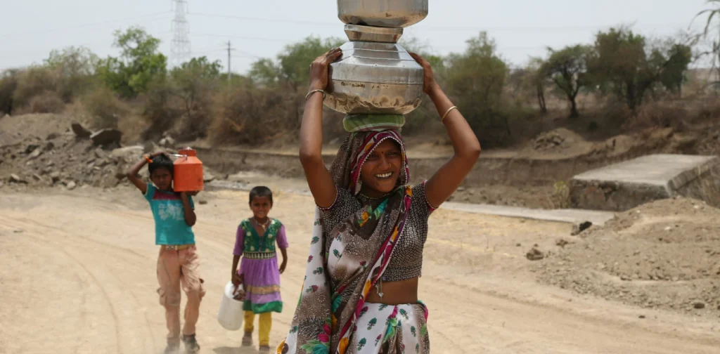 a woman and two children each carrying a bucket of water
