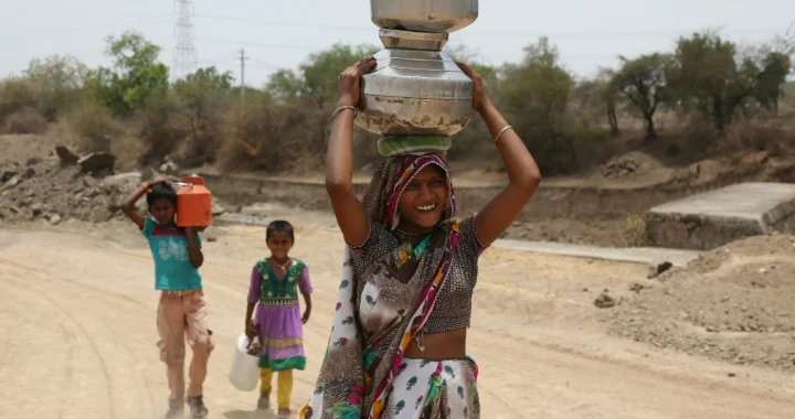 a woman and two children each carrying a bucket of water