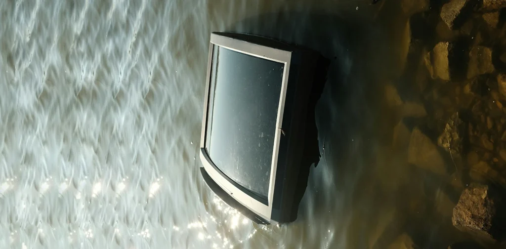a television submerged in murky water