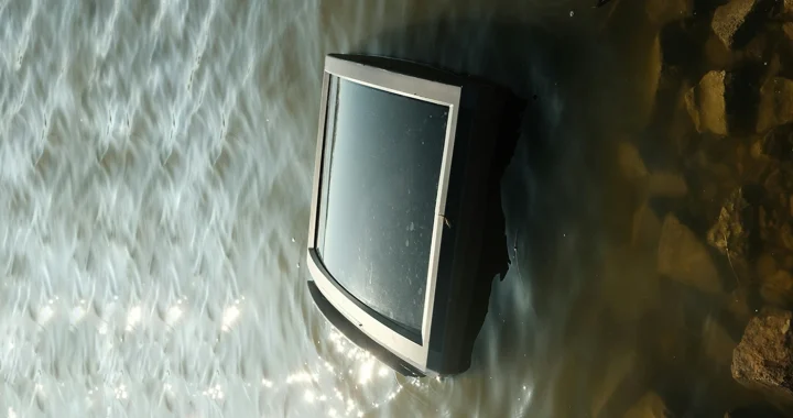 a television submerged in murky water