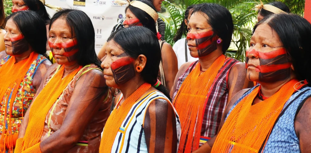 Indigenous women with painted faces and orange scarves