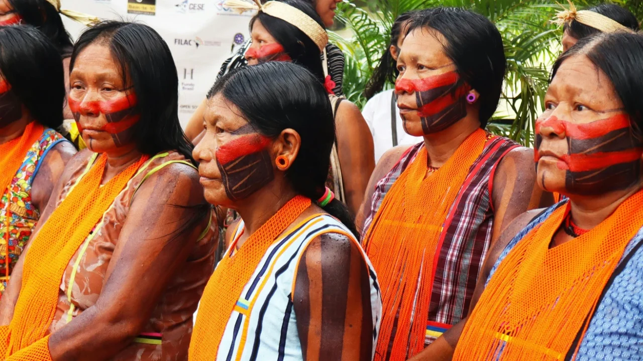 Indigenous women with painted faces and orange scarves